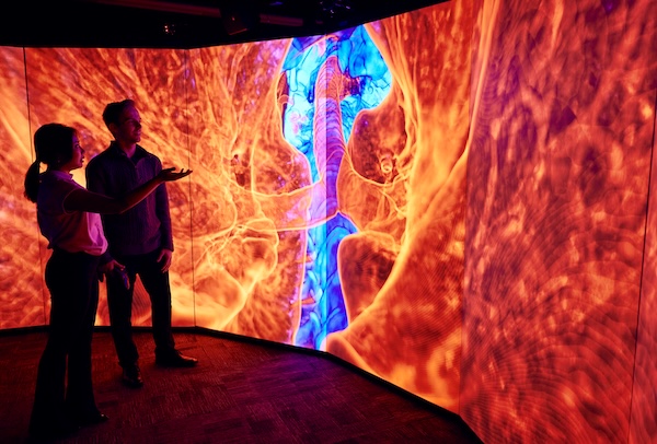 Graduate students working in a 10-sided walk-in virtual reality system displaying a medical image.